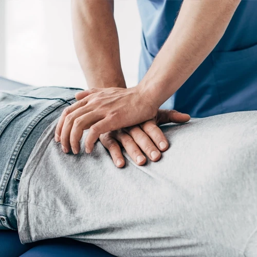 A chiropractor adjusting a patient's lower back while they lay on an adjustment table